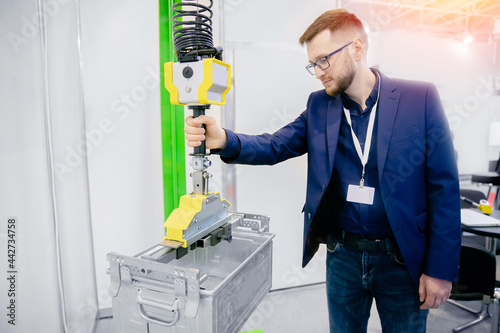 Worker engineer uses intelligent industrial manipulator lift easy with gripper in factory photo