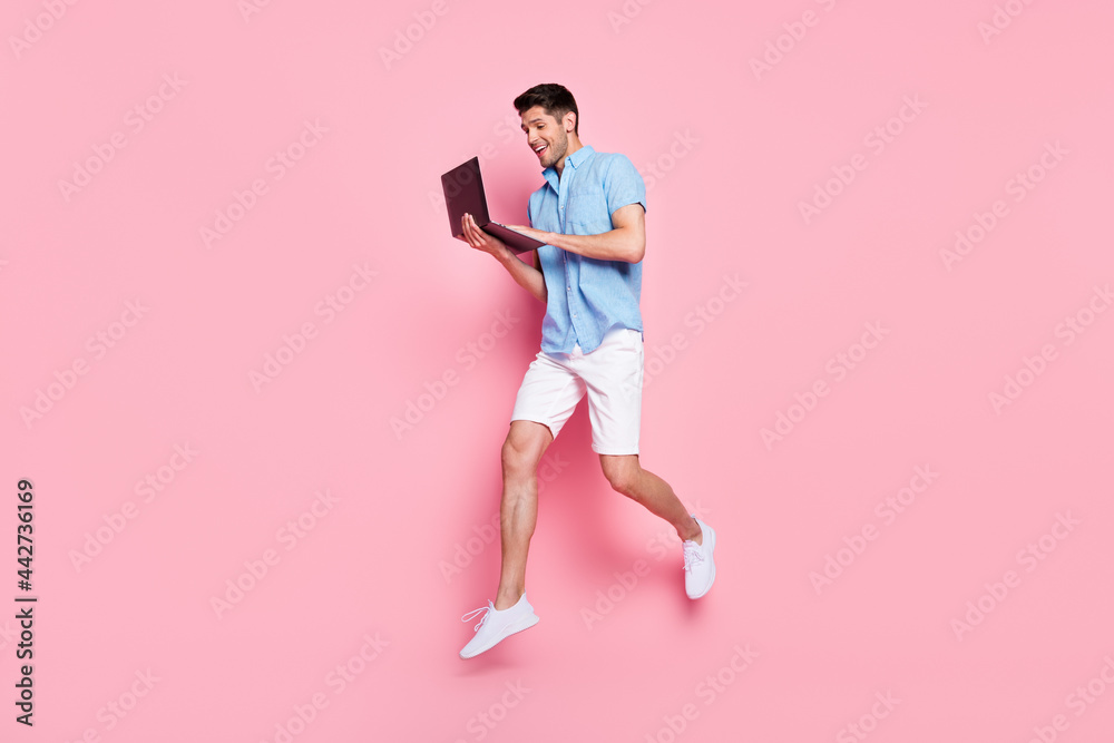 Full length body size photo man working on computer jumping high isolated pastel pink color background