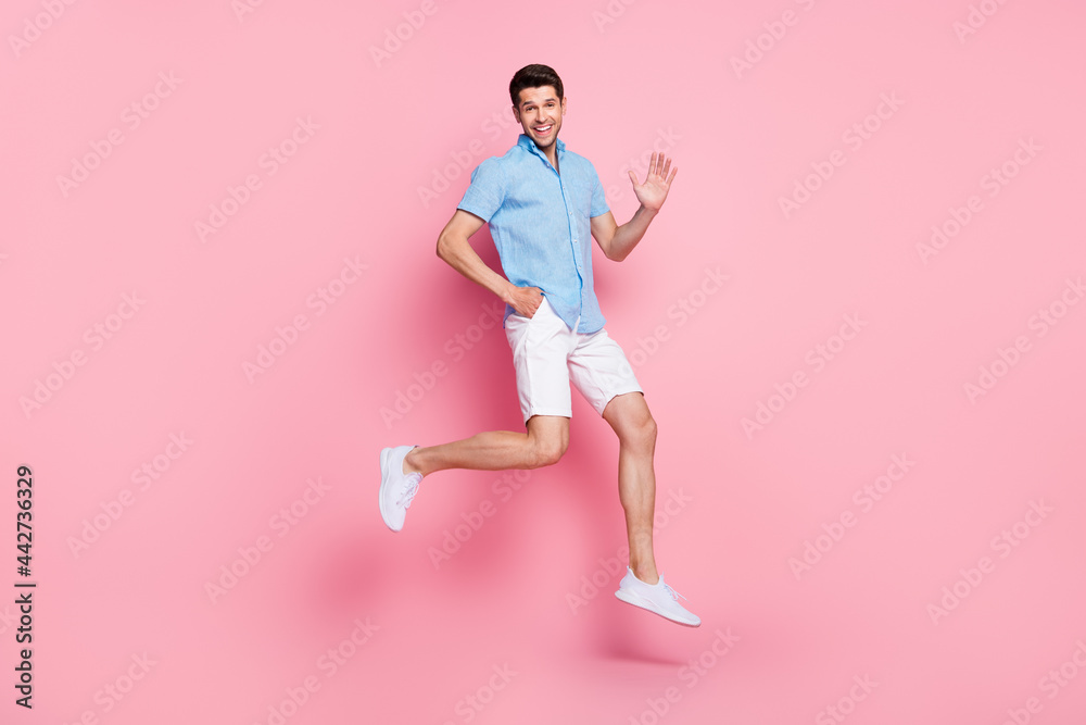Full length body size photo man jumping in summer clothes waving hand isolated pastel pink color background