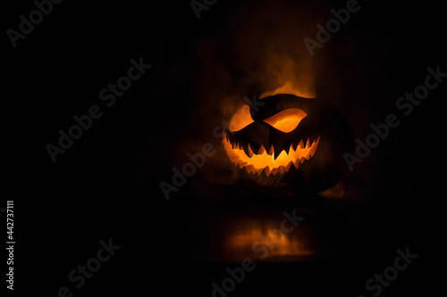 Halloween pumpkin smile and scary eyes for party night. Close up view of scary Halloween pumpkin with eyes glowing inside at black background