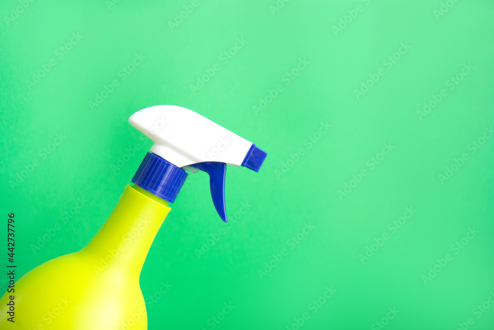 Plastic spray yellow bottle isolated on green background. Bottle for detergent or for plant spraying