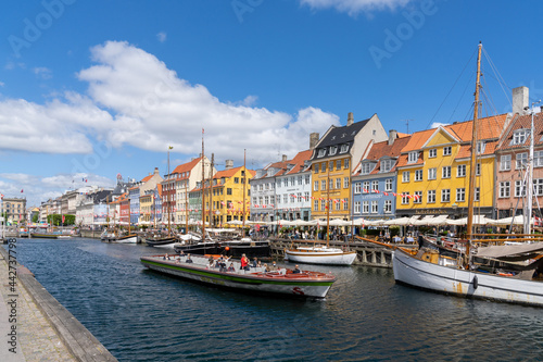 view of the historic Nyhavn quarter in downtown Copenhagen with a tourist boat cruise barge in the foreground