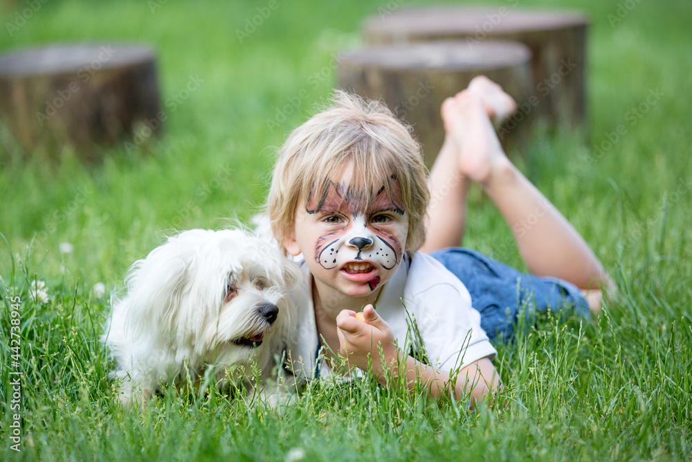 Little toddler baby boy, child with painted face as a dog, playing with pet dog in the garden Little toddler baby boy, child with painted face as a dog, playing with pet dog in the garden