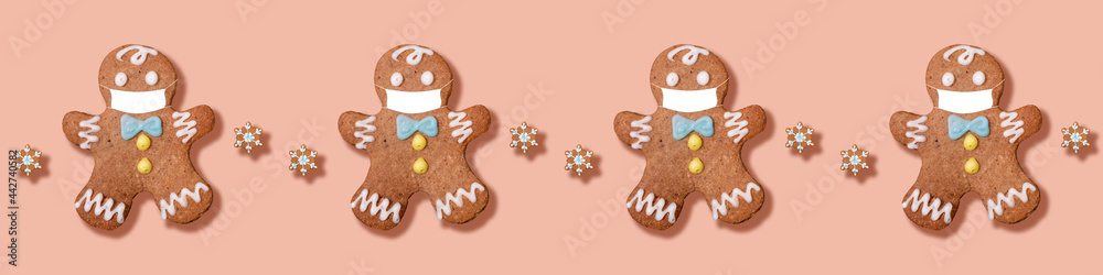 Christmas banner with seamless pattern of gingerbread men in medical masks separated by snowflakes on pink backdrop. Christmas banner with seamless pattern of gingerbread men in medical masks separated by snowflakes on pink backdrop.