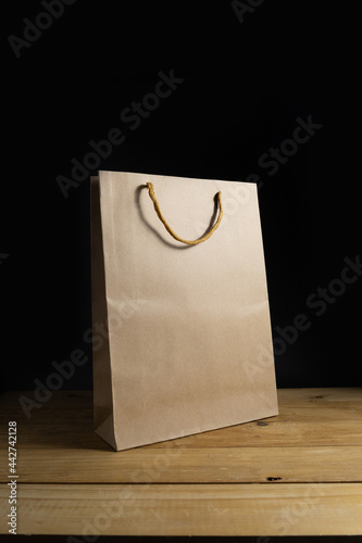 Blank shopping bag mockup on wooden table isolated black background.