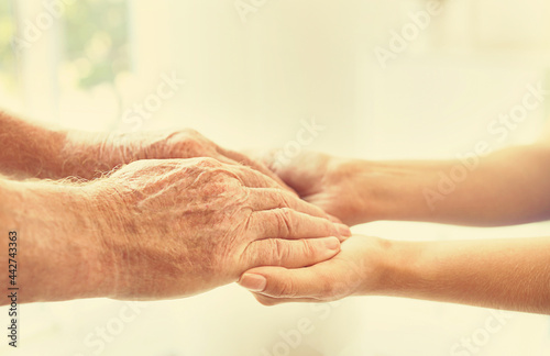 Helping hands on blurred background, closeup. Elderly care concept