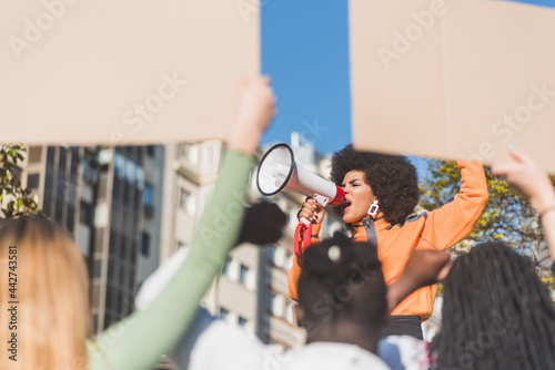 Black protester speaking into loudspeaker against unrecognizable multiethnic people outdoors