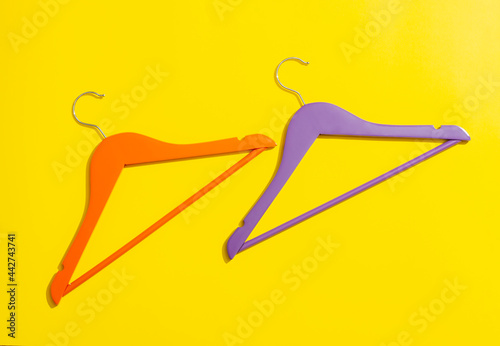 Orange and purple wooden hanger on yellow background in close-up.