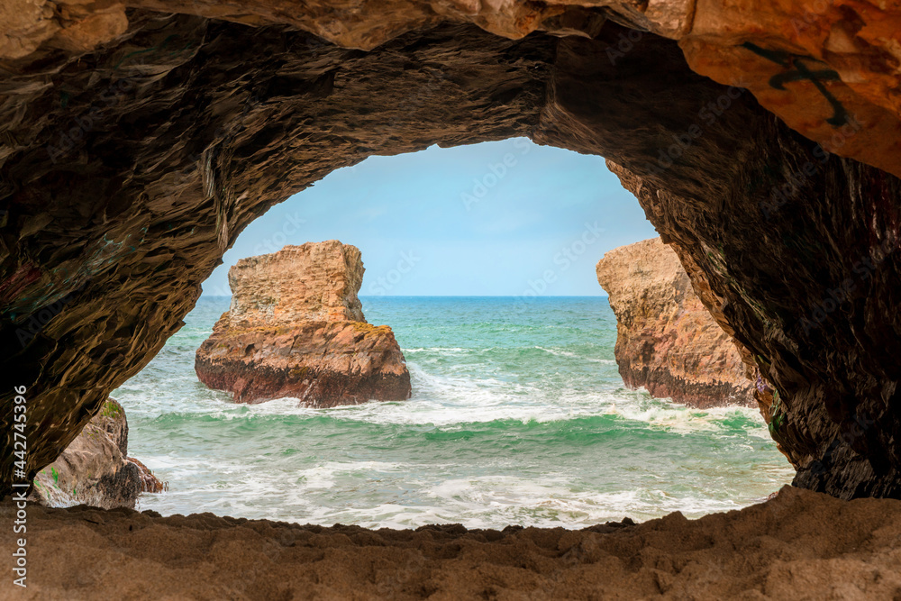 A dark cave with a picturesque view of the waves of the Pacific Ocean and the rocks, California
