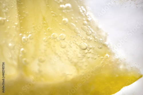 Bubbles from a slice of lemon in lemonade with ice.