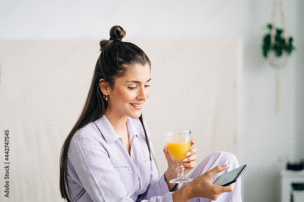 Charming woman with beverage on smartphone at home Charming woman with beverage on smartphone at home
