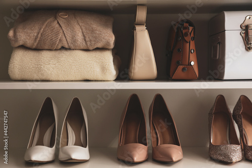 Obraz na plátně Stylish women's shoes, clothes and bags on shelving unit
