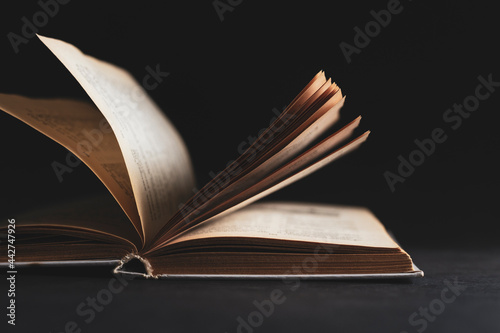 Open book with pages on a black background.