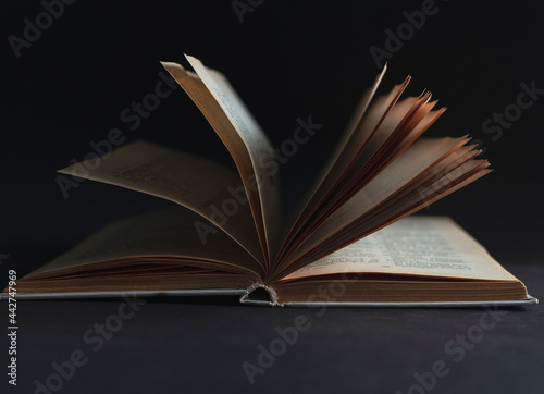 Open book with pages on a black background.
