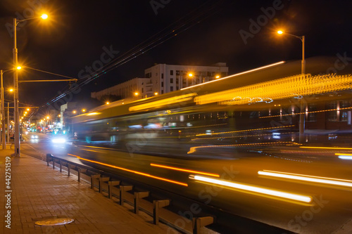 The movement of a blurred bus along the overpass in the evening.