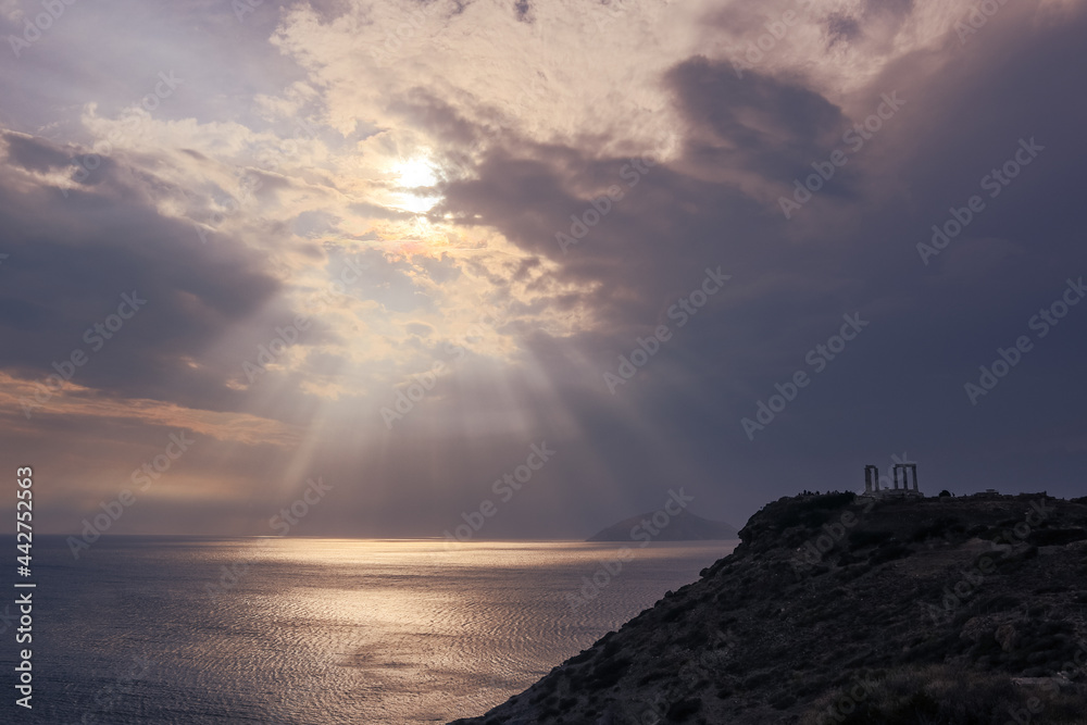 Sunset over the Temple of Poseidon at Cape Sounion, Greece. Cliff with epic sunset view on mediterranean sea and ruins of an ancient Greek temple with columns