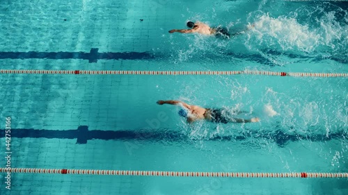 Swim Race: Two Professional Swimmers jump dive in Swimming Pool, Stronger and Faster Wins. Athletes Compete the Best Wins Championship, World Record. Slow Motion, Aerial Top View Tracking Shot
