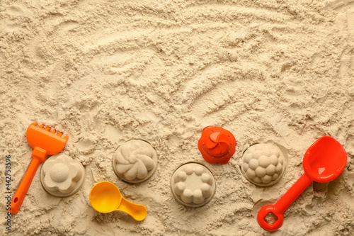Flat lay of beach toy kit on sand, space for text. Outdoor play