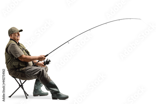 Profile shot of a mature fisherman sitting on a chair with a fishing rod
