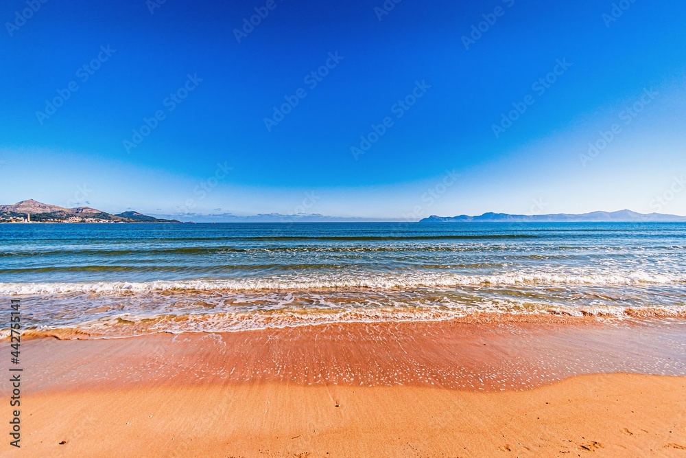 crystal clear sea on a warm sunny day with blue sky in playa de muro beach in mallorca, spain