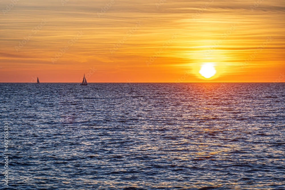 sunset over the sea. orange sky and two small boat in the distance. mallorca, spain