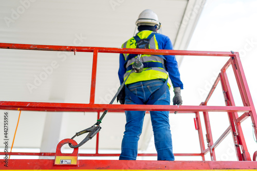 Worker on a Scissor Lift Platform working at site focus on full harness safety belt	 photo