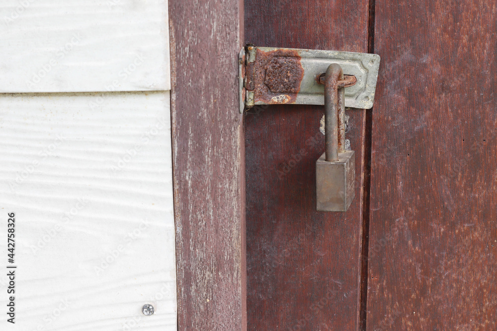 Old and rusty padlock locked at the wooden door closeup. Old and rusty padlock locked at the wooden door closeup.