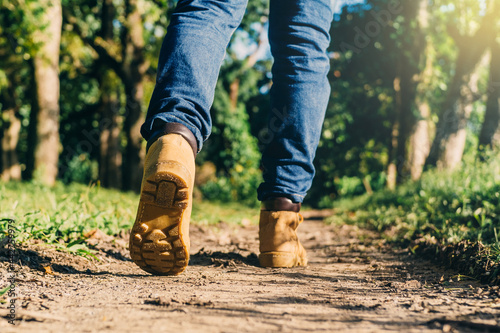 close up feet of an unrecognizable person wearing boots to travel walking in a green forest. travel , hiking and mountain concept.