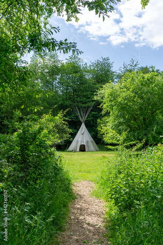 gravel hiking path leads up to a large teepee in the forest photo