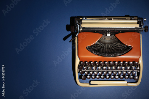 Vintage typewriter on dark blue background, top view. Space for text