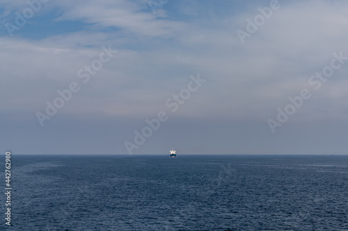 large freight ship travelling full steam ahead and approaching from far away on the open ocean