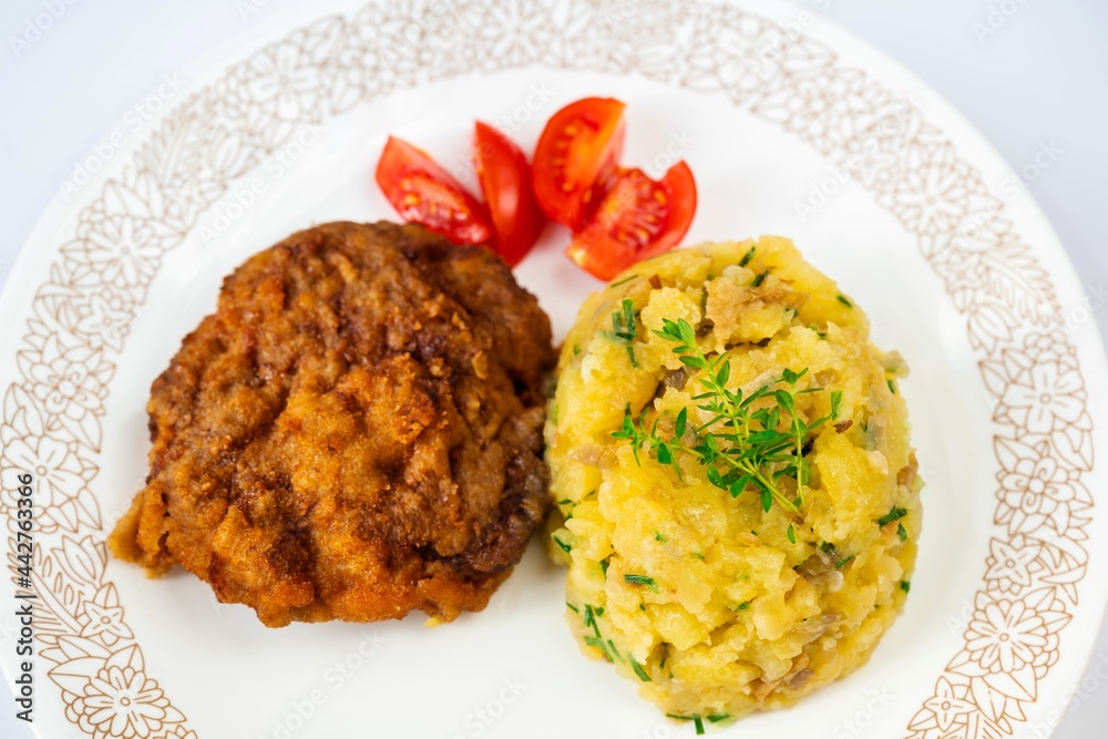 Fried fillet from chopped beef in breadcrumb, mashed potato and sliced cherry tomato. Fried fillet from chopped beef in breadcrumb, mashed potato and sliced cherry tomato.