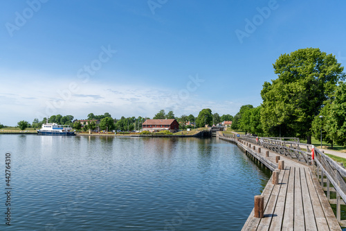 idyllic lake with a wooden boardwalk along the side and sailboats moored in the background