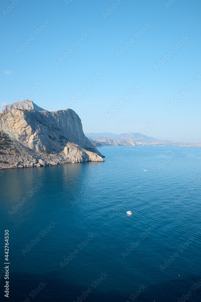 rocky shore in the sea, wild beach and mountains, the rock goes into the water, sea view, wild landscape