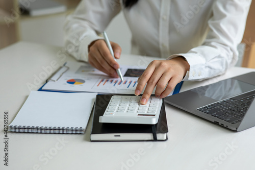 Financial Business women  use calculator analyze the graph of the company s performance to create profits and growth  Market research reports and income statistics  Financial and Accounting concept.