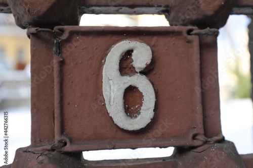 Vintage grunge square metal rusty plate of number of street address with number. Close up, brand.