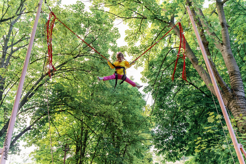 Fényképezés happy child girl jumping up on a bungee