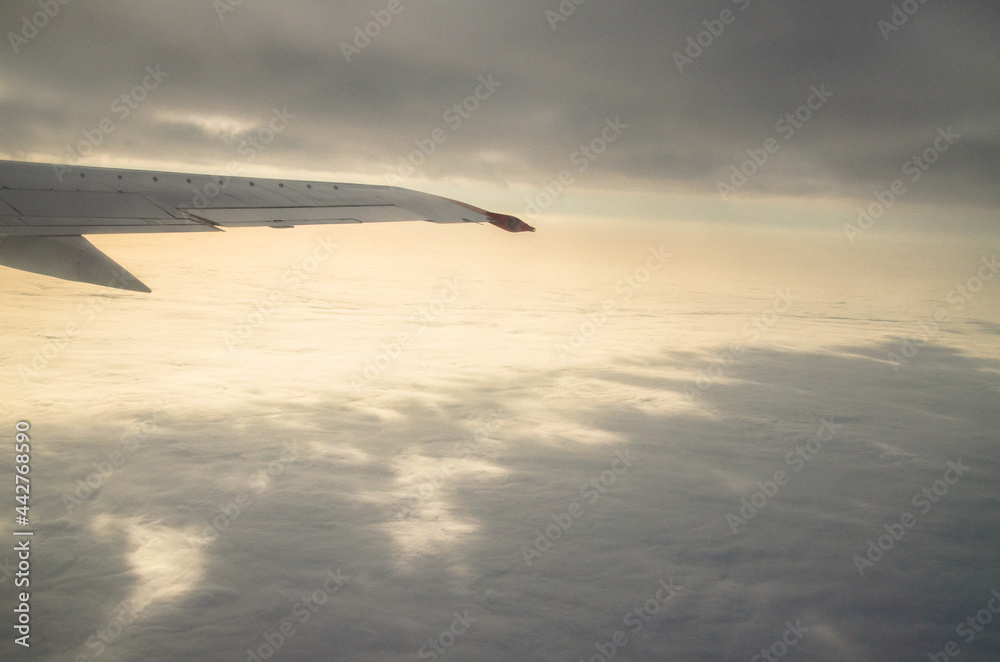 The wing of an airplane flying in the sky above the clouds