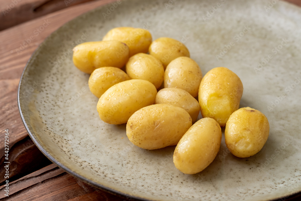 Boiled young small potatoes on a plate on a wooden background. Boiled young small potatoes on a plate on a wooden background.