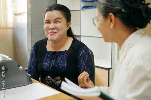 Fotografie, Tablou Happy Asian blind person woman with vintage braille typewriter or Brailler for people with vision disabilities, working and talking with senior colleague woman in office workplace