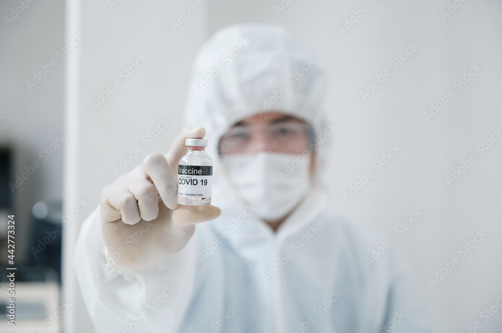 Scientist man in medical protective ppe showing effective vaccine bottle against Covid-19, Coronavirus in the lab Scientist man in medical protective ppe showing effective vaccine bottle against Covid-19, Coronavirus in the lab