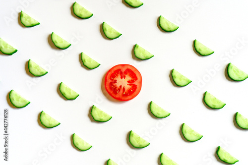 Fototapeta Naklejka Na Ścianę i Meble -  repeating pattern of sliced semicircles of fresh raw vegetable cucumbers for salad and a slice of tomato in the center isolated on a white background flat lay, top view