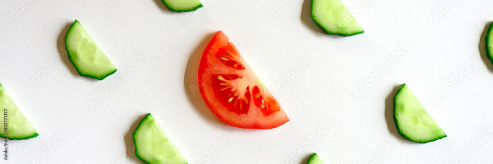 repeating pattern of sliced semicircles of fresh raw vegetable cucumbers for salad and a slice of tomato in the center isolated on a white background flat lay, top view. banner repeating pattern of sliced semicircles of fresh raw vegetable cucumbers for salad and a slice of tomato in the center isolated on a white background flat lay, top view. banner