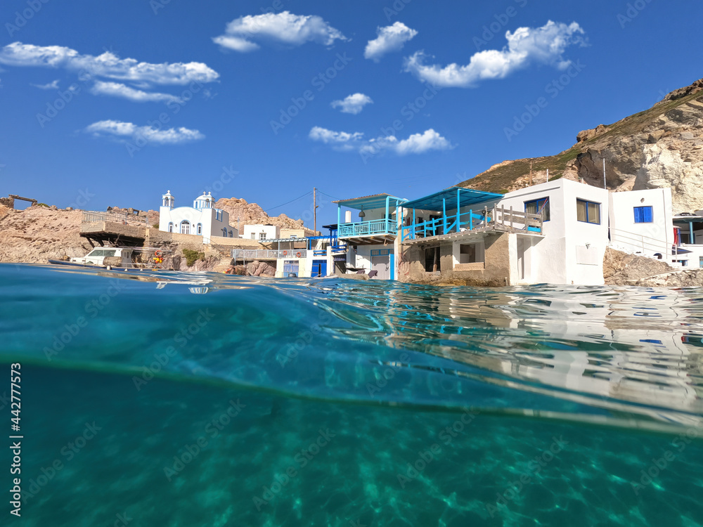 Underwater split photo of famous traditional fisherman settlement of Firopotamos with colourful boat houses called sirmata, Milos island, Cyclades, Greece