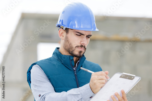 portrait of smiling handyman signing invoice on clipboard