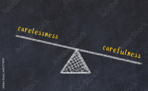 Chalk drawing of scales with words carelessness and carefulness. Concept of balance photo