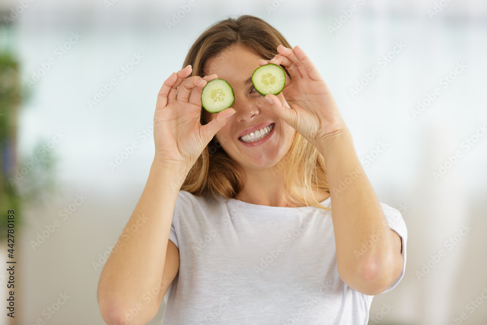 young woman covering her eyes with cucumber slices young woman covering her eyes with cucumber slices