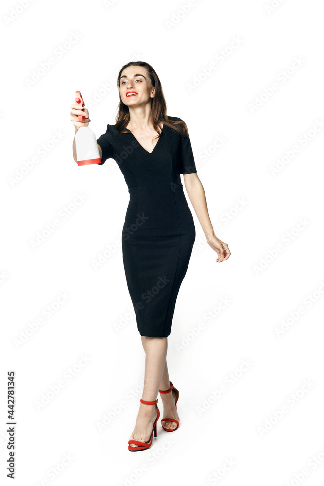 The fatal woman in a black dress with a spray for washing glasses pretending to be a secret agent, holding a spray. Isolated on a white background. The fatal woman in a black dress with a spray for washing glasses pretending to be a secret agent, holding a spray. Isolated on a white background.