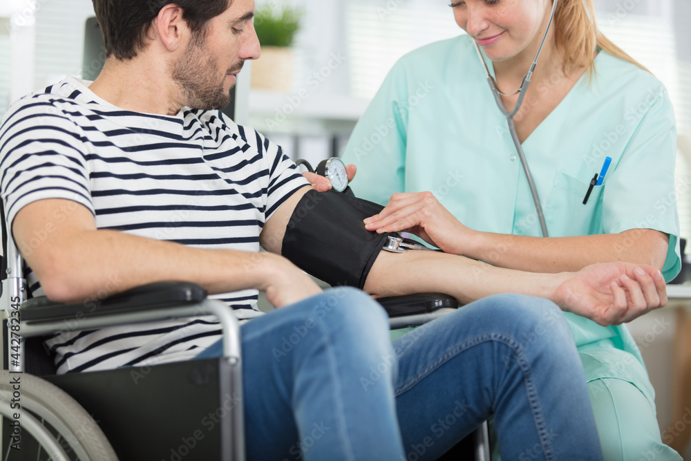 Fototapeta premium young attractive nurse checking the patients hypertension