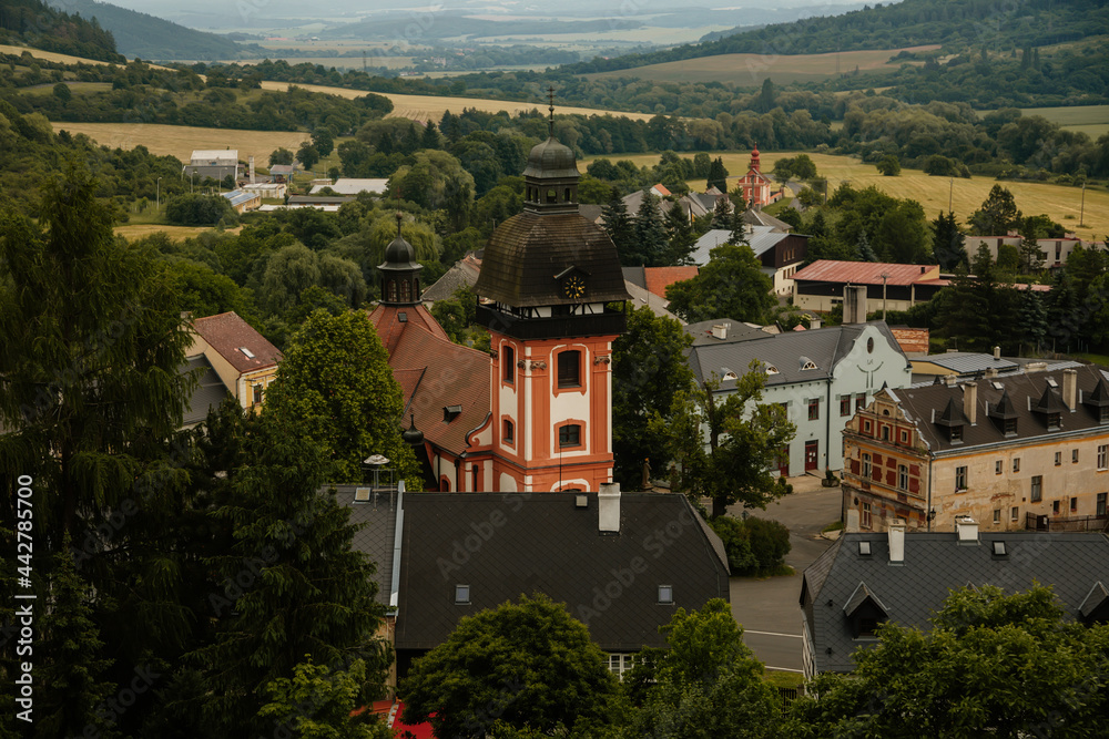 Valec, Western Bohemia, Czech Republic, 19 June 2021: Church of the Nativity of St. John the Baptist with prismatic tower with shingle roof in center of old town at summer day